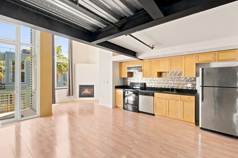 A modern kitchen with wooden floors and stainless steel appliances.