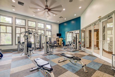 A spacious gym with a variety of equipment and a ceiling fan.