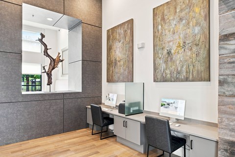 A reception area with a desk, chairs, and two paintings on the wall.