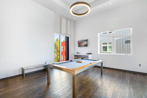 A pool table in a room with wood flooring and white walls.