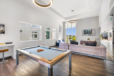 A pool table is in the middle of a room with a couch and a window.