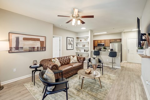 A living room with a brown couch and a ceiling fan.