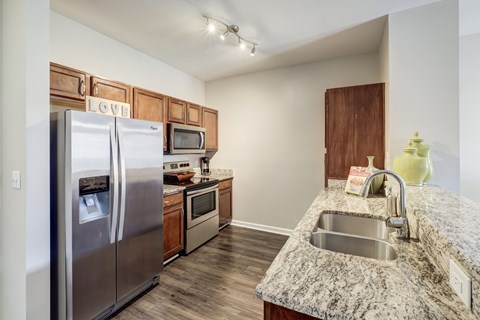 A kitchen with a granite counter top and stainless steel appliances.