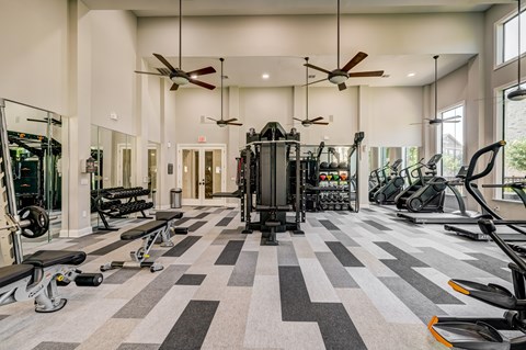 A spacious gym with a variety of equipment and a treadmill in the center.