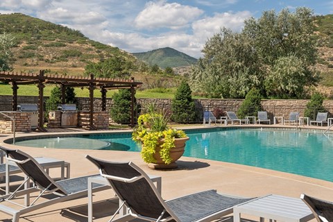 A pool surrounded by chairs and a mountain in the background.