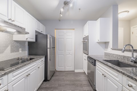A kitchen with white cabinets and a black refrigerator.