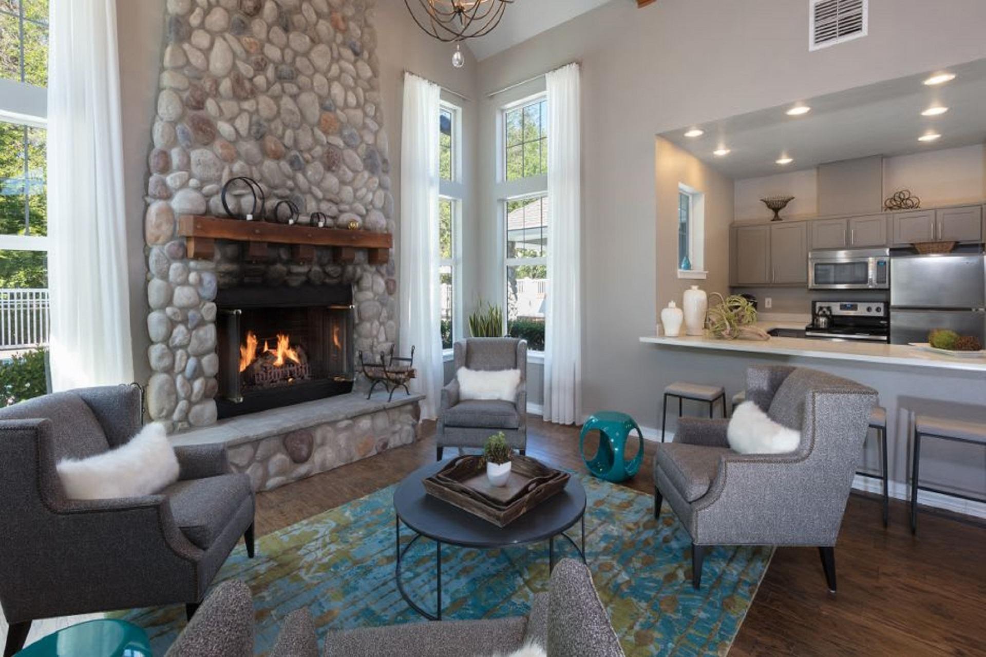 A living room with a stone fireplace and a dining table with chairs.