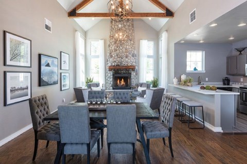 A dining room with a fireplace and grey chairs.