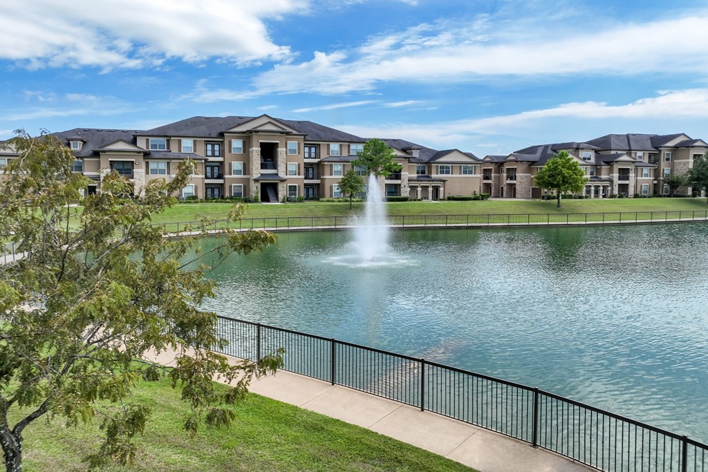 pathway near the lake with a fountain at The Falls at Copper Lake apartments