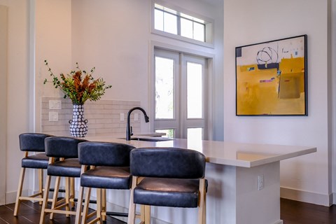 A kitchen with a white counter and blue chairs.