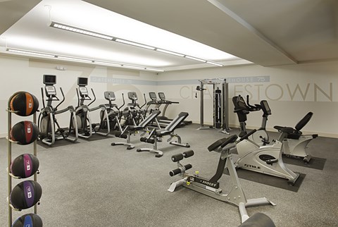 A gym with a variety of exercise equipment including treadmills, stationary bikes, and weight machines.