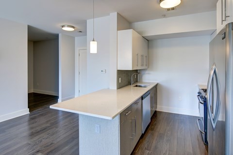 A kitchen with a white counter top and stainless steel appliances.