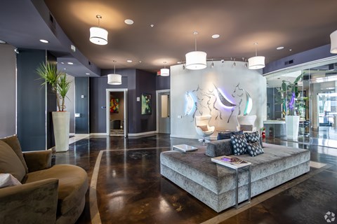 A modern living room with a brown sofa and a large artwork on the wall.