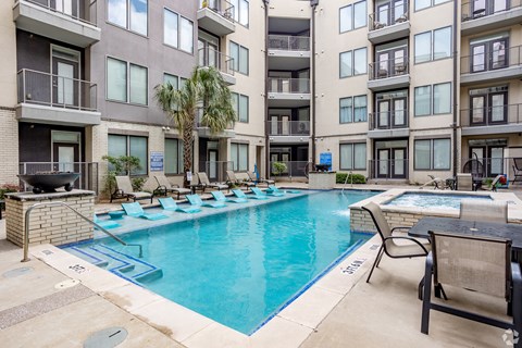 A swimming pool surrounded by lounge chairs and palm trees.