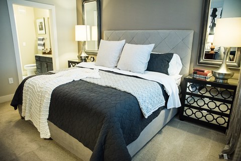 A bedroom with a large bed and a nightstand with a lamp.