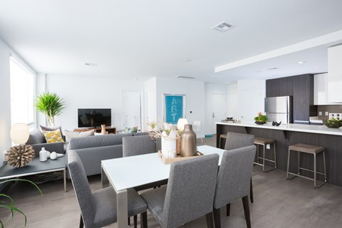 A modern dining room with a white table and grey chairs.
