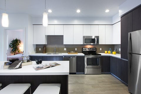 A modern kitchen with a stainless steel refrigerator, a microwave above the stove, and a dining table with chairs.
