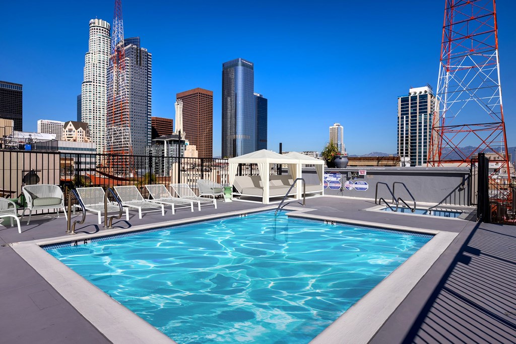 A pool on a rooftop with a city skyline in the background.
