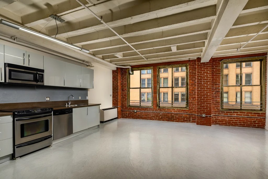 A spacious kitchen with stainless steel appliances and a brick wall.
