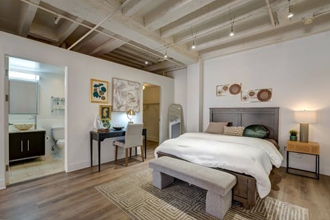 A bedroom with a large bed and a desk with a chair.