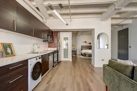 A modern kitchen with dark wood cabinets and a green couch.
