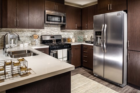 A modern kitchen with a stainless steel refrigerator and wooden cabinets.