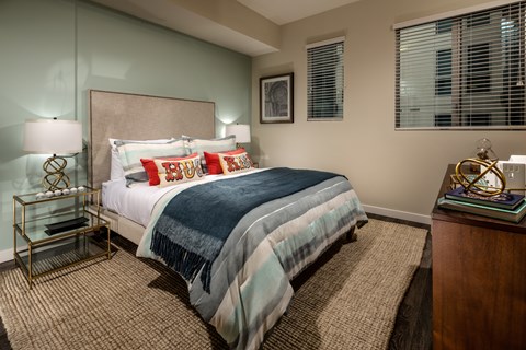 A bedroom with a bed, nightstand, and lamp.