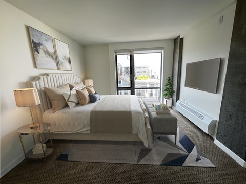 A bedroom with a large bed and a window overlooking the city.