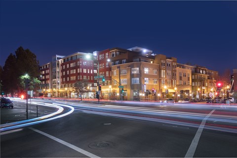 A long exposure shot of a city street at night with light trails from moving vehicles.