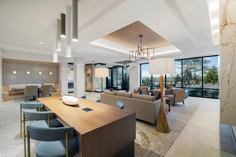 A modern living room with a long wooden table and grey chairs.