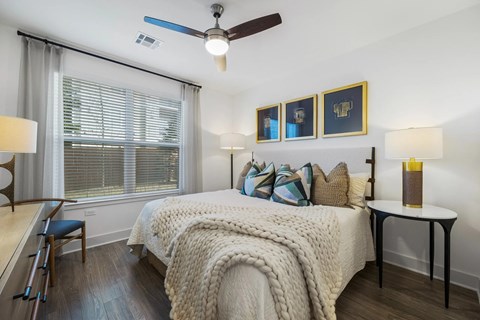 A bedroom with a bed, a chair, a table, and a window.