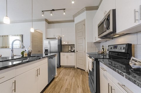 A modern kitchen with white cabinets and black countertops.