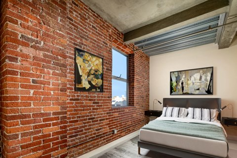 A bedroom with a brick wall and a bed.