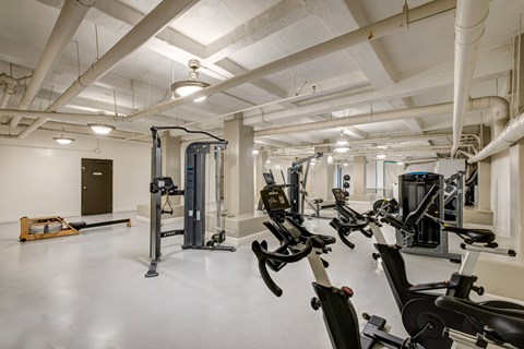 A gym with a variety of exercise equipment including treadmills, stationary bikes, and weight machines.