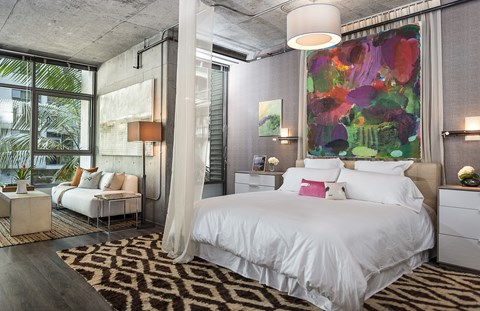 A bedroom with a large bed and a painting on the wall.