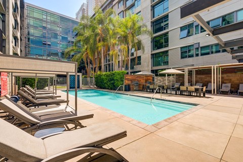 A pool surrounded by chairs and a building in the background.