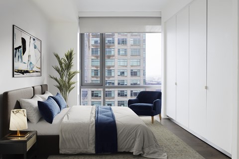 A bedroom with a large bed and a blue chair.