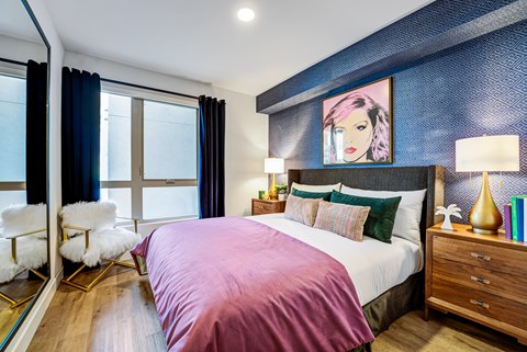 A bedroom with a large bed and a painting of a woman's face on the wall.