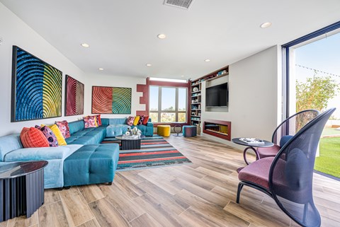 A living room with a blue couch and a large painting on the wall.