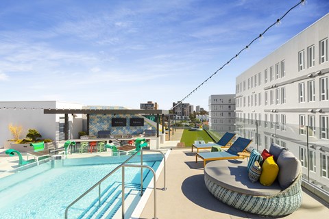 A pool area with a hot tub and lounge chairs.