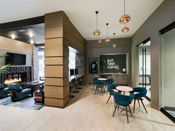 A modern coffee shop with a fireplace and a sign that says "But first, coffee.".