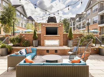 A patio with a couch, chairs, and a fireplace.