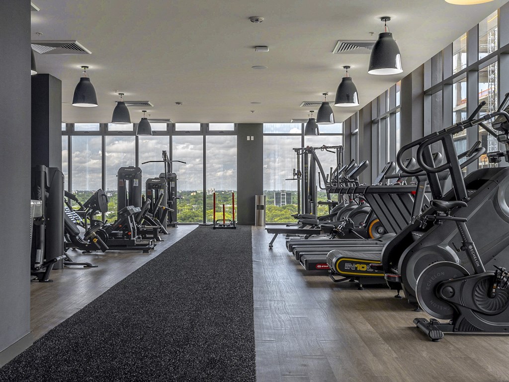a fitness center with weights machines and a view of the city