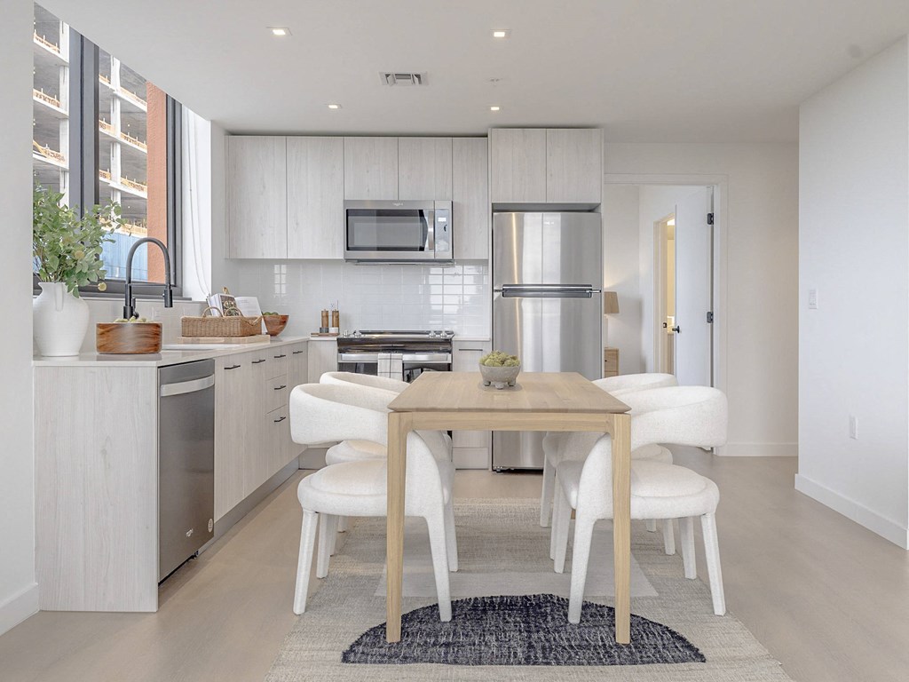 a white kitchen with a wooden table and white chairs