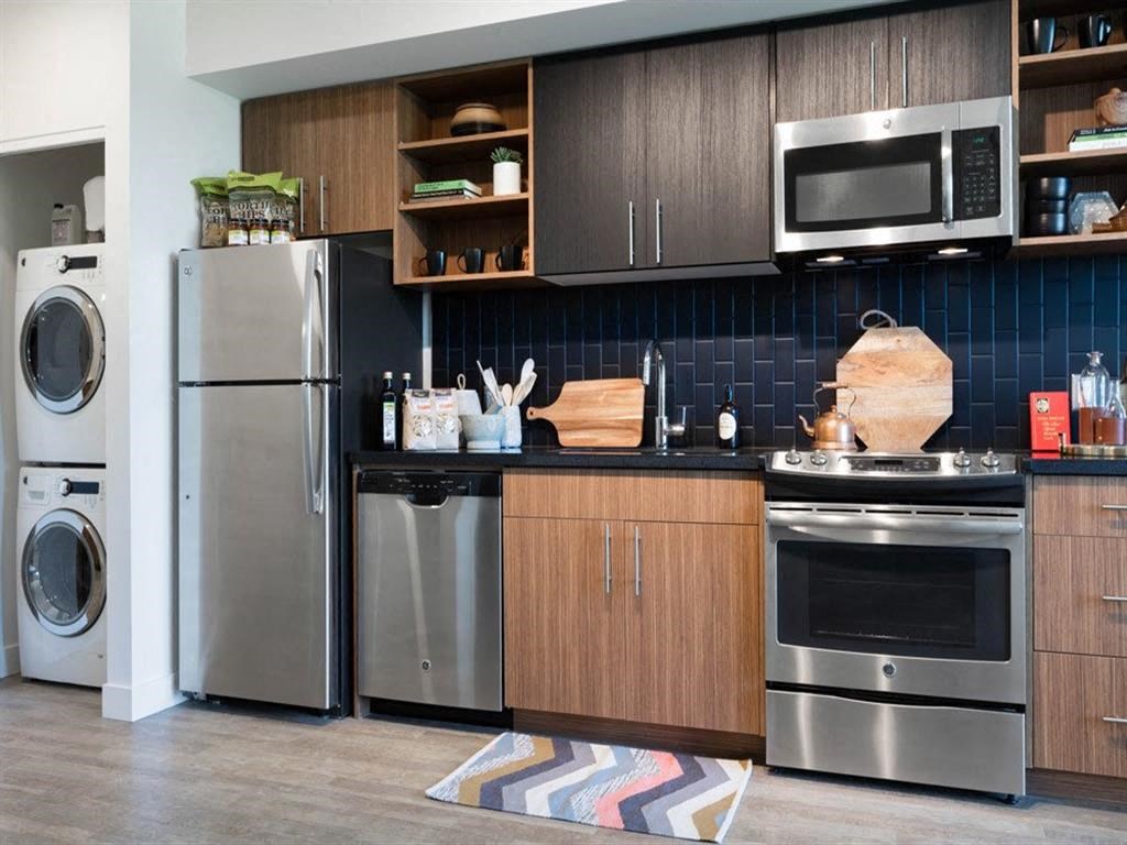 Kitchen with stainless steel appliances and blue subway tile backsplash at Cook Street Apartments, Portland
