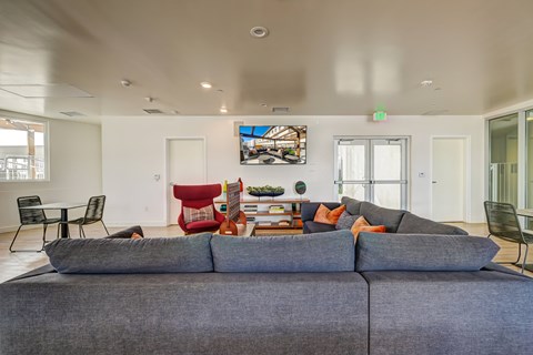 A living room with a grey couch and a painting on the wall.