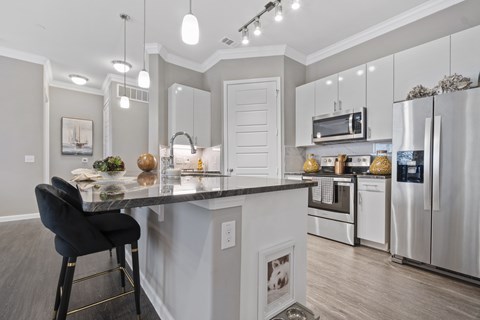 A modern kitchen with a black chair and a marble countertop.