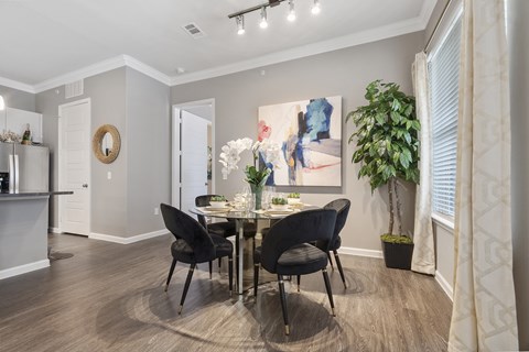A dining room with a table set for two and a potted plant.