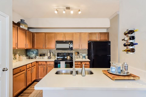 A kitchen with wooden cabinets and a black refrigerator.