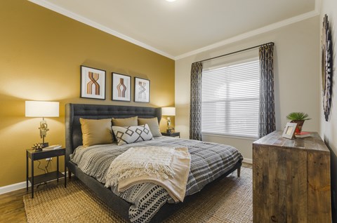 A bedroom with a large bed and a wooden dresser.